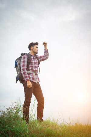 Portrait of young hipster man outdoor raising hands with backpack on his shoulder, Adventure tourism.の写真素材