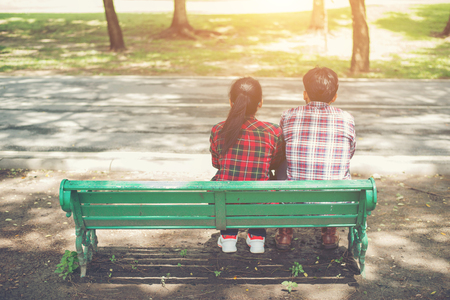 Young teenagers couple in love sitting together on the bench in the park .の写真素材
