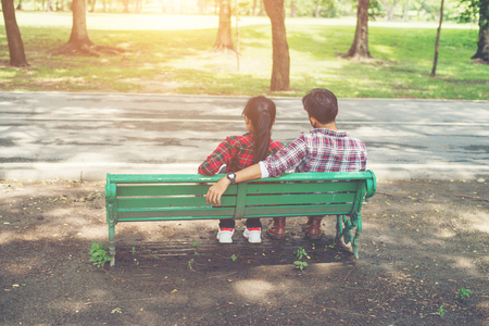 Young teenagers couple in love sitting together on the bench in the park .の写真素材