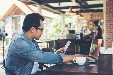 Hipster man drinking coffee while using tablet computer at cafe.の写真素材