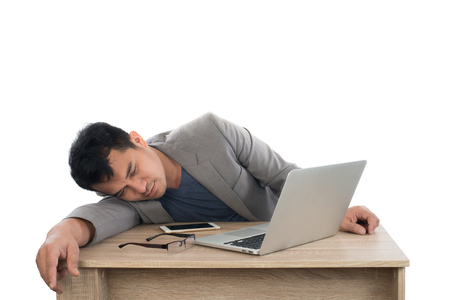 Businessman sleeping next to his laptop computer with white background.の写真素材