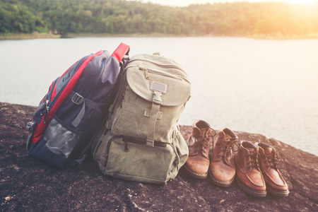 Backpacks and shoes with nature lake background.の写真素材