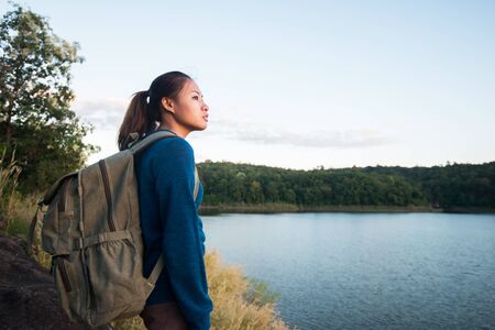 Young hiker woman standing on the rock and enjoying sunset over lake.の写真素材