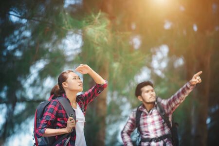 Young couple stop looking for something during hiking together. Man pointing on the treeの写真素材