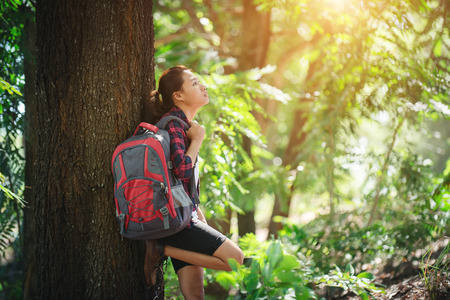 Tired hiker woman relaxes with a large backpack during walk in the forest.の写真素材