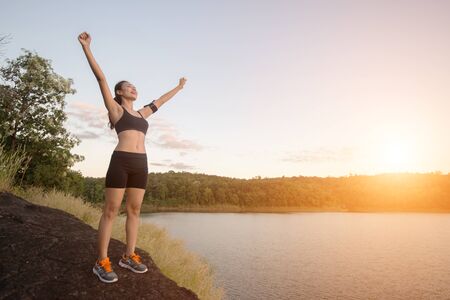 Young fitness woman achieve hiking on peak with lake view sunset.の写真素材