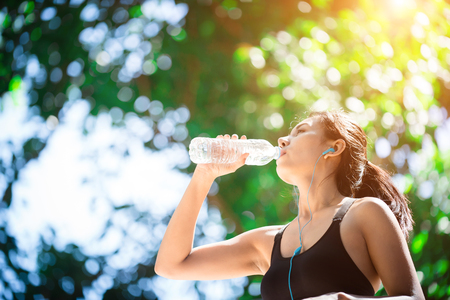 Young woman engaged in sports while listening to music. Take a resting and drinking water.の写真素材