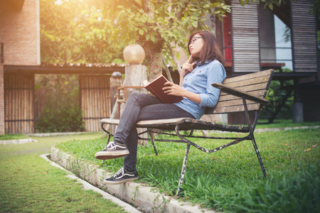 Hipster charming girl relaxing in the park while read book, Enjoy nature around.の写真素材