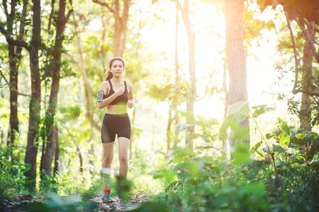 Young woman jogging on rural road in green forest nature.の写真素材