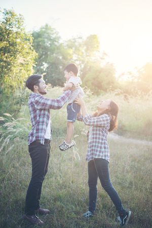 Happy young family spending time together outside in green nature park. Family love concept.の写真素材