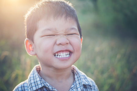 Close up of cute asian boy playing and smiling outdoors. Cute little boy on field. Summer holiday play in the park.の写真素材