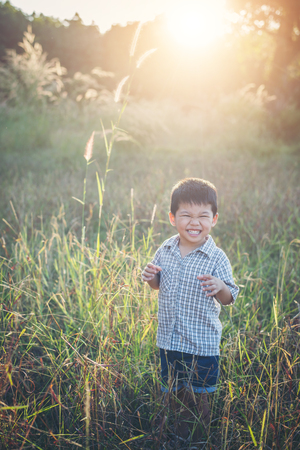 Happy little asian boy playing outdoors. Enjoy life. Cute asian boy on field.の写真素材