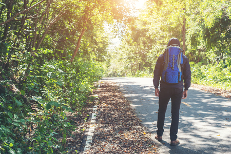 Rear of hiker man walking on the rural road on vacation. Holiday tourism concept.の写真素材
