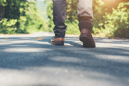 Man feet walking on the rural road on vacation. Holiday tourism concept.の写真素材