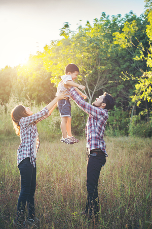 Happy young family spending time together outside in green nature park. Family love concept.の写真素材