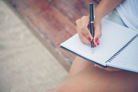 Close up of woman hand writing on notepad.