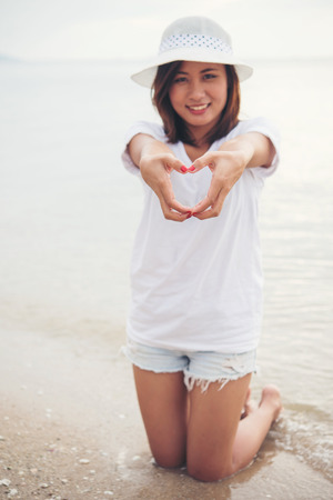 Happy young woman playing on beach make a heart shape at the vacation time.の写真素材