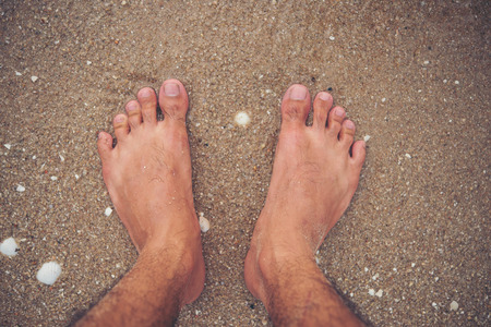 Young man feet on the beach.