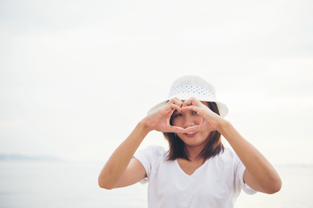 Happy young woman playing on beach make a heart shape at the vacation time.の写真素材