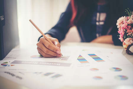 Business woman holding a pencil is working with business chart grpah checking infomation inside.の写真素材