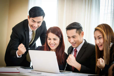 Happy business team enjoy good news together from email on laptop.の写真素材