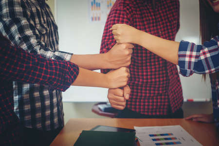 Happy business people putting their fist on top showing success business teamwork.