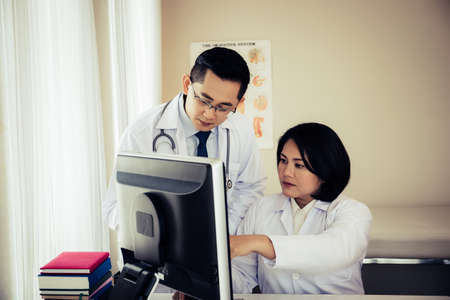 Group of doctors looking at computer on meeting at hospital ward.の写真素材