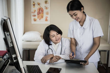 Nurse consulting about document to the doctor at her workplace.の写真素材