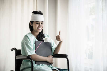 Female patient sitting in a wheelchair holding her documents in her hand. Injury and healing...
