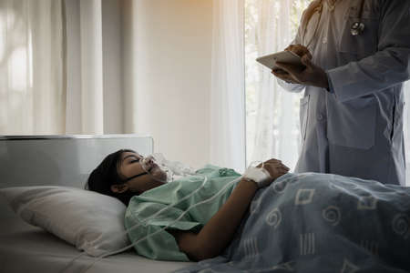 Doctor writing on clipboard while looking at patient in hospital.の写真素材
