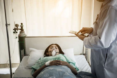 Doctor writing on clipboard while looking at patient in hospital.の写真素材