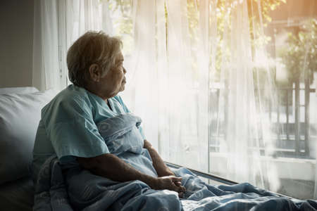 Elderly patients sitting in bed waiting for relatives to visit with loneliness.の写真素材
