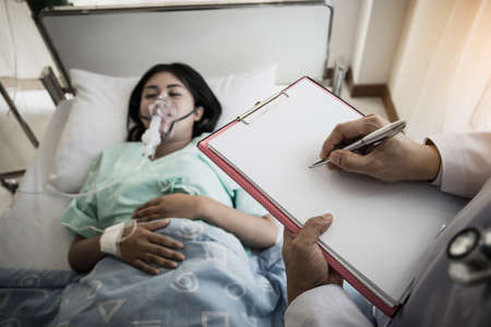 Close up of Doctor writing on clipboard while looking at patient in hospital.