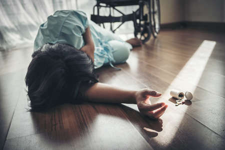 Female patients fall unconscious from a wheelchair on the floor. Heart attack, patients do not help themselves.の写真素材