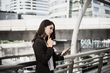 Attractive business woman using a digital tablet while standing in front of office building.の写真素材