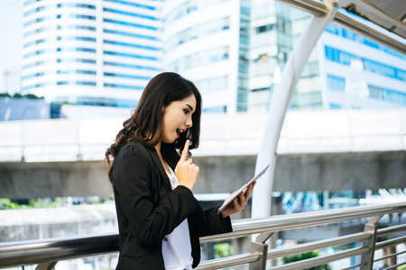 Attractive business woman using a digital tablet while standing in front of office building.の写真素材