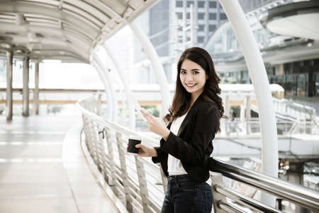 Image of busy female calling on the phone and reading document while going to workの写真素材