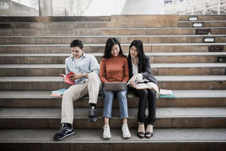 Group students studying researching on laptop Together sitting at college.の写真素材