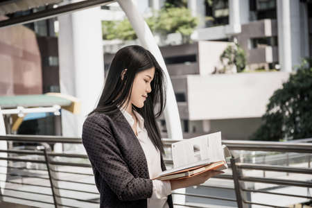 Young business woman standing reading the business report during a walking to meeting.の写真素材