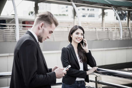 Business colleagues working together and talking on phone while going to office.の写真素材