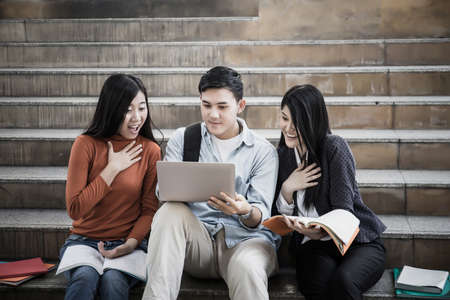 Group students studying researching on laptop Together sitting at college.の写真素材