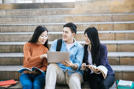 Group students studying researching on laptop Together sitting at college.の写真素材