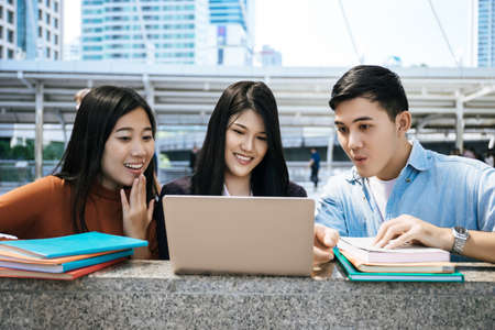 Group of students studying researching on laptop Together sitting at college.の写真素材