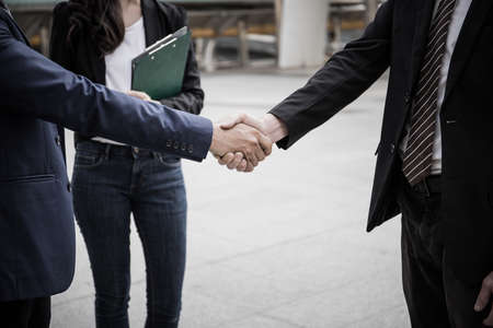 Business partner work hands shaking while looking at successful work at tablet. Business concept.の写真素材