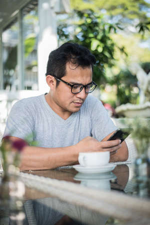 Handsome man using mobile phone at the cafeの写真素材