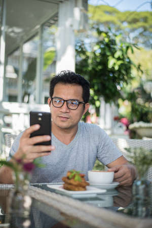 Handsome man using mobile phone at the cafeの写真素材