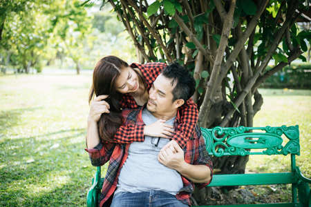 Young couple in nature sitting on bench, male and female togetherの写真素材