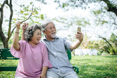 Senior couple taking a selfie photo with smart phone in a parkの写真素材