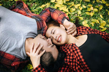 Romantic couple of young people lying on grass in park.の写真素材