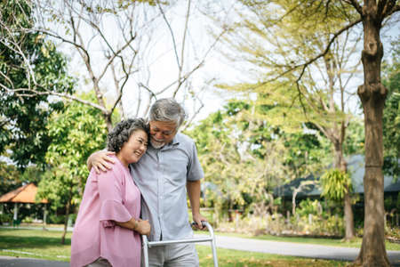 assisting her senior patient who's using a walker for supportの写真素材